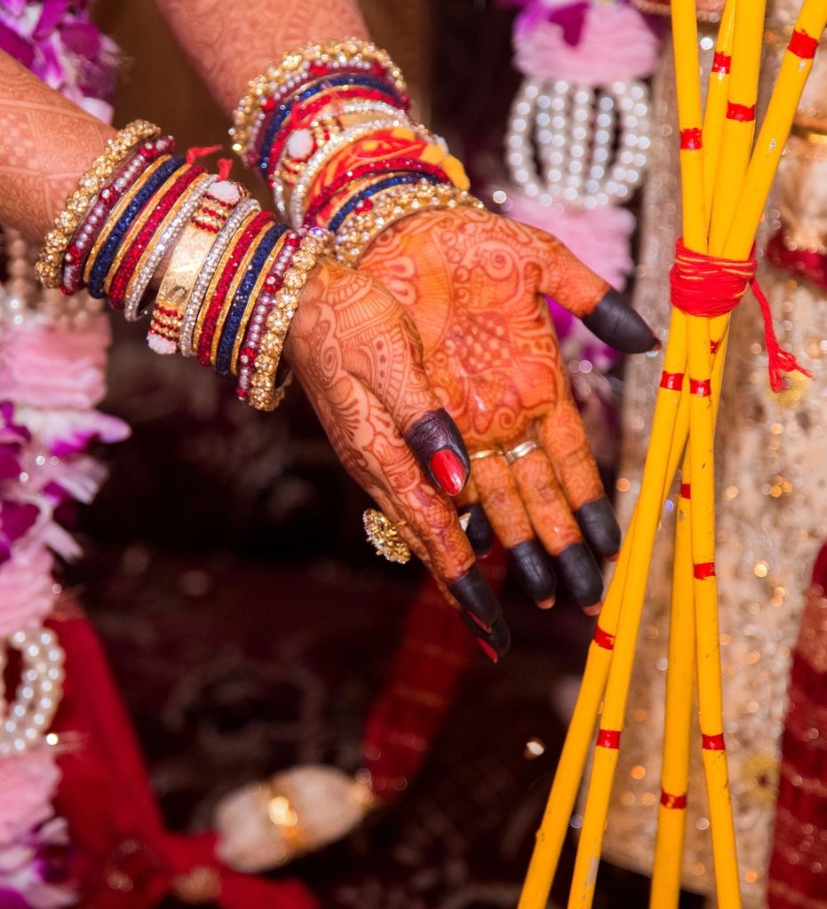A bride's hands with mehndi and bangles during a wedding ceremony